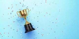 Photo: A small gold trophy with a black base lies on a light blue background, surrounded by red, white, and blue confetti.