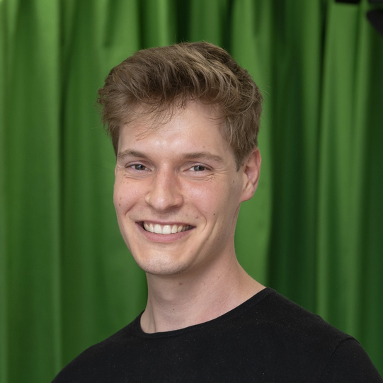 Photo: Profile picture of Tobias Schmidt. He is wearing a black pullover and has short blond hair. Background: green screen.