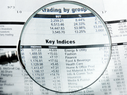 Photo: A magnifying glass focuses on stock market data on a newspaper page.