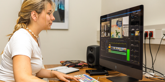 Photo: A female student is editing video material on a computer.