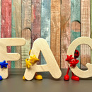 Photo: Beige bold letters F, A and Q are held by small figurines in blue, yellow and red 
